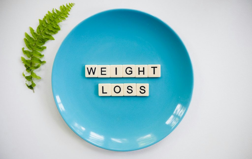 pexels photo 2377045 2377045 A blue plate with 'weight loss' tiles and a fern leaf on white background.