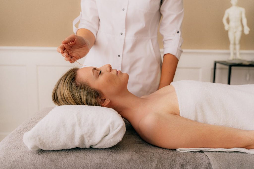 woman-lying-down-for-massage-6076147 A woman receiving a relaxing acupuncture session on a massage table indoors.